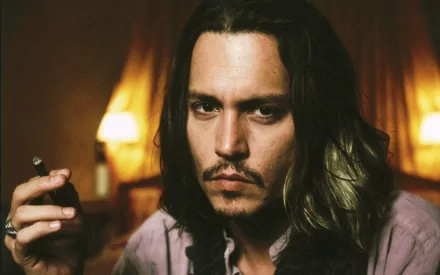 A close-up portrait of Johnny Depp featuring long hair, a moustache, and a cigar. The background suggests a warm, intimate setting, creating a captivating atmosphere.