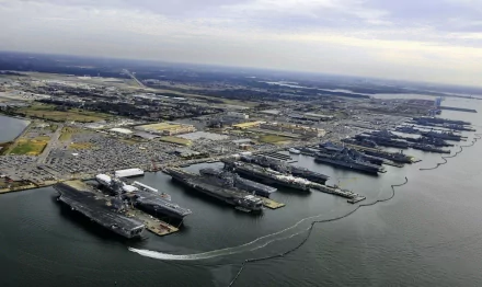 Aerial view of a naval base featuring multiple aircraft carriers docked in the water, with a sprawling landscape of land and sea in a high-definition desktop wallpaper.