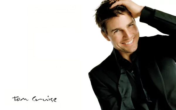 HD desktop wallpaper featuring Tom Cruise, smiling and slightly tilting his head, dressed in a black jacket against a white background. The image includes his signature in the bottom left corner.