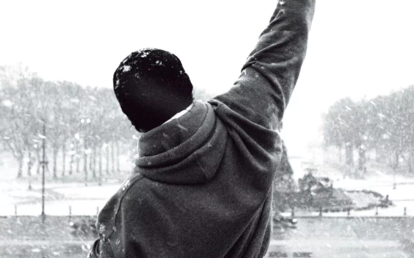 A powerful black-and-white image of Rocky Balboa raising his arm triumphantly against a snowy backdrop, serving as an inspirational HD PC desktop wallpaper and background.