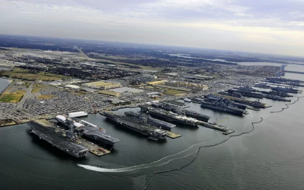 Aerial view of a naval base featuring multiple aircraft carriers docked in the water, with a sprawling landscape of land and sea in a high-definition desktop wallpaper.