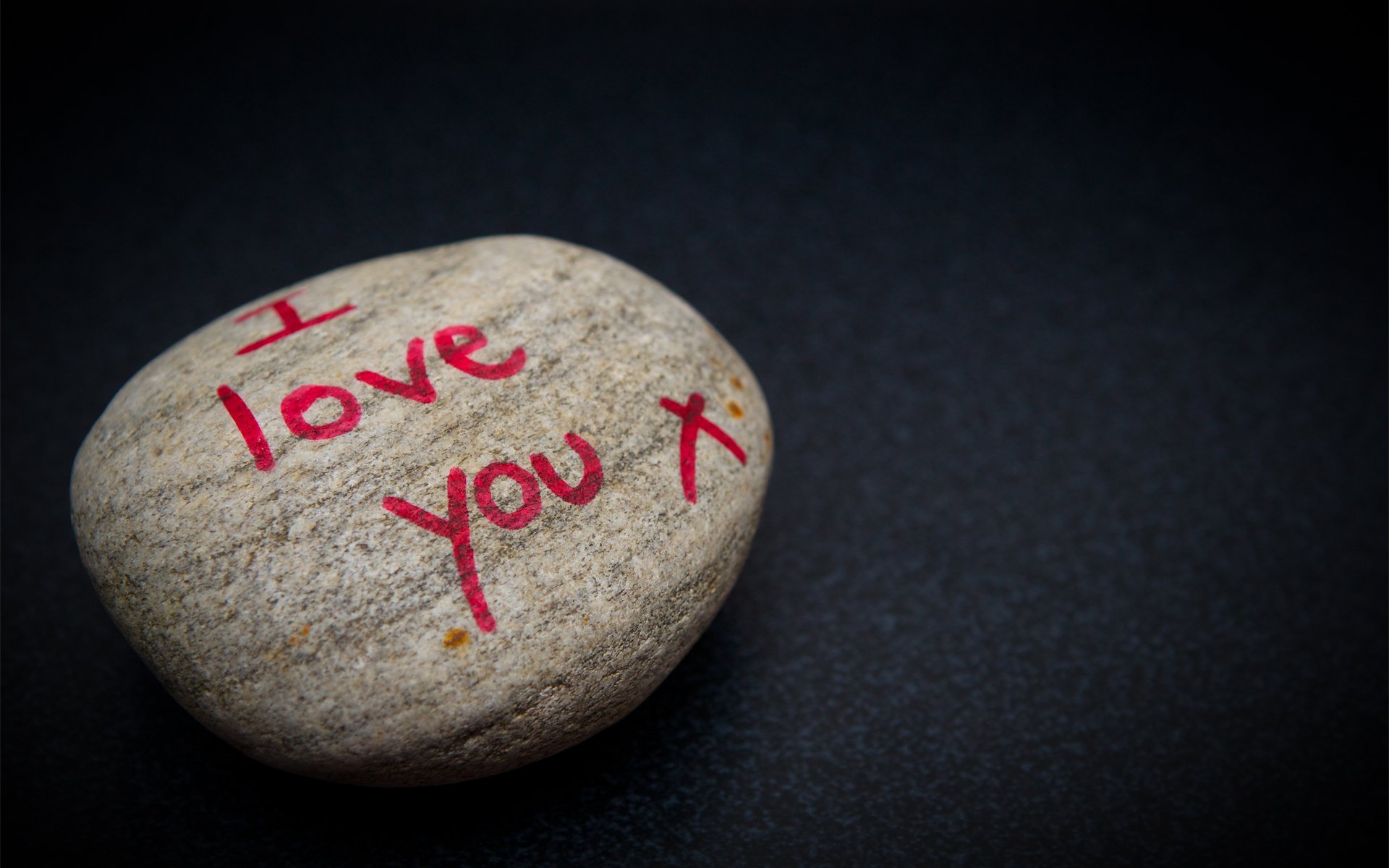 A close-up of a rock with I love you written in red on a dark background, creating an artistic and heartfelt HD desktop wallpaper.