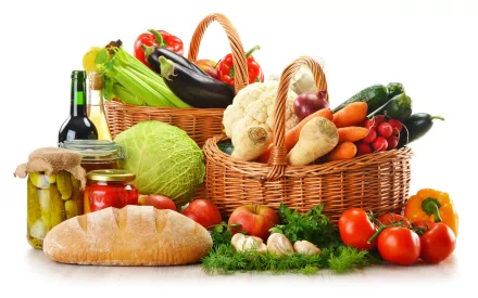 HD PC desktop wallpaper featuring an assortment of fresh vegetables, bread, jars, and a bottle of wine arranged in wicker baskets on a white background.