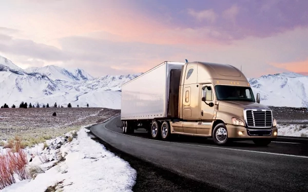 HD desktop wallpaper featuring a Freightliner truck driving on a mountainous road with snowy terrain and a colorful sky in the background.