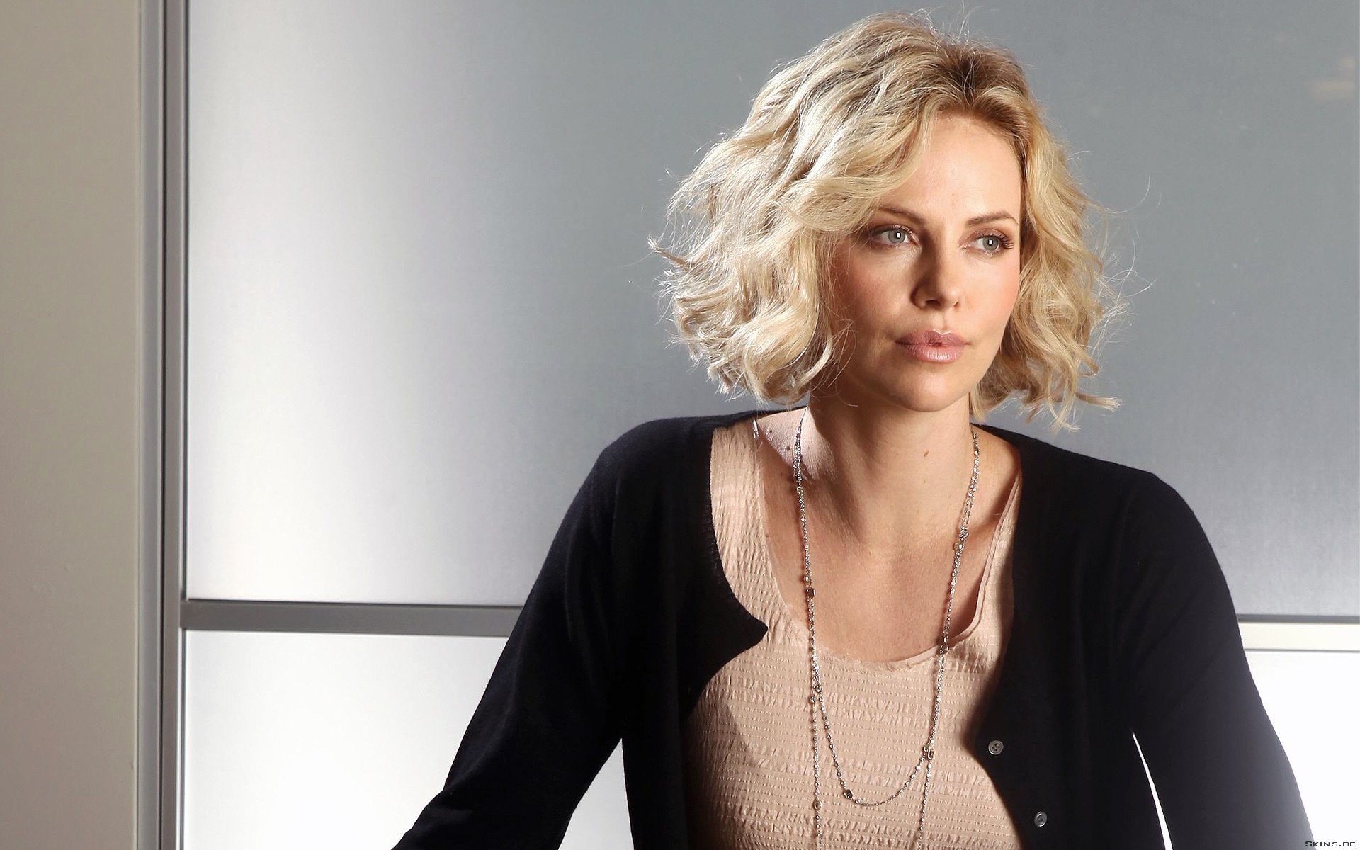 Charlize Theron poses elegantly in this high-definition desktop wallpaper, showcasing her iconic style and charisma against a sleek background.