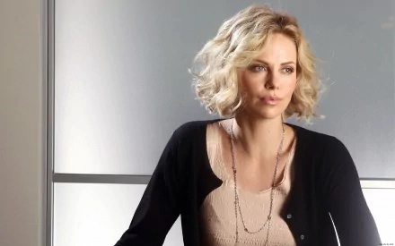 Charlize Theron poses elegantly in this high-definition desktop wallpaper, showcasing her iconic style and charisma against a sleek background.