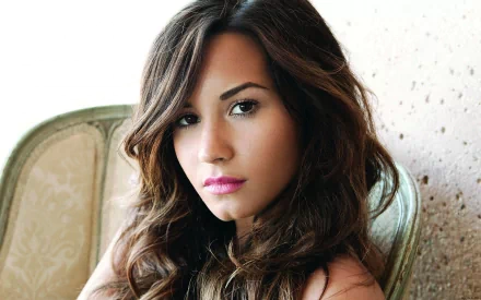 Demi Lovato gazes confidently at the camera in this HD music-themed desktop wallpaper, showcasing her striking features and glamorous style.