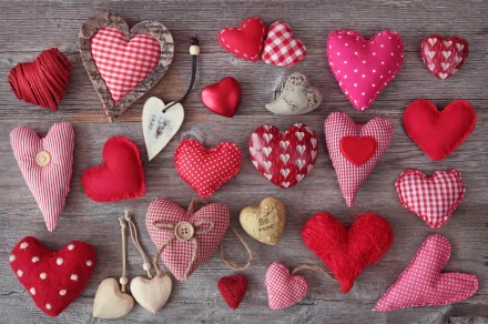 A vibrant collection of artistic hearts in various textures and patterns, featuring shades of red and pink, displayed against a rustic wooden background. 4K Ultra HD desktop wallpaper.