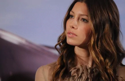 HD desktop wallpaper featuring celebrity Jessica Biel with soft waves in her hair and a contemplative expression against a muted background.