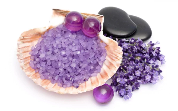 HD desktop wallpaper featuring a still life arrangement of purple spa stones, lavender flowers, and a shell filled with purple bath salts, blending natural and man-made elements.
