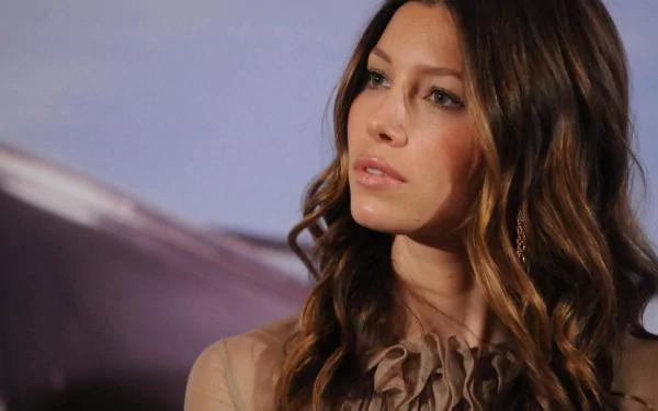 HD desktop wallpaper featuring celebrity Jessica Biel with soft waves in her hair and a contemplative expression against a muted background.