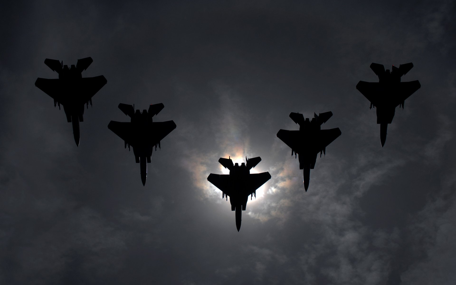 Silhouettes of five McDonnell Douglas F-15 Eagle fighter jets flying in formation against a cloudy sky, captured in this HD military desktop wallpaper.