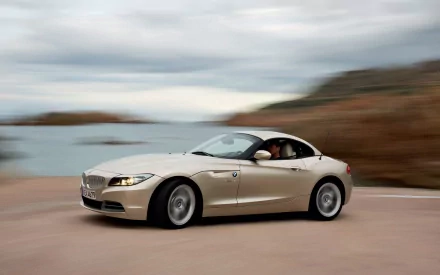 A silver BMW Z4 Roadster speeding along a coastal road, captured in an HD desktop wallpaper showcasing the sleek design of the BMW Z4 vehicle.
