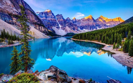 A serene nature scene featuring a tranquil lake reflecting majestic mountains under a bright sky, surrounded by lush forests—an inspiring HD desktop wallpaper.