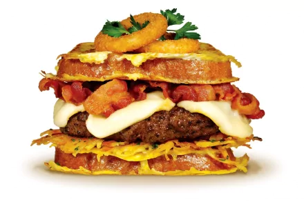 HD PC desktop wallpaper showcasing a stacked sandwich with bacon, melted cheese, onion rings, and fresh herbs, highlighting rich textures and vibrant colors.