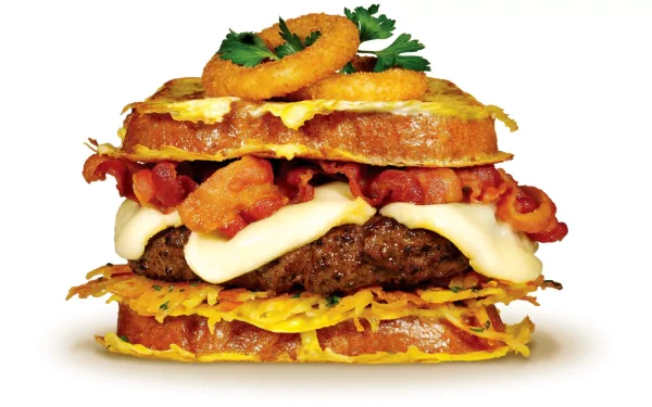 HD PC desktop wallpaper showcasing a stacked sandwich with bacon, melted cheese, onion rings, and fresh herbs, highlighting rich textures and vibrant colors.