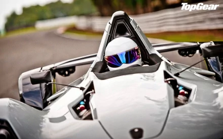 HD desktop wallpaper from Top Gear featuring a close-up of The Stig driving a high-performance vehicle on a track.
