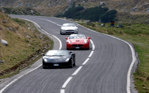 HD Top Gear wallpaper featuring three high-performance cars driving on a winding mountain road.