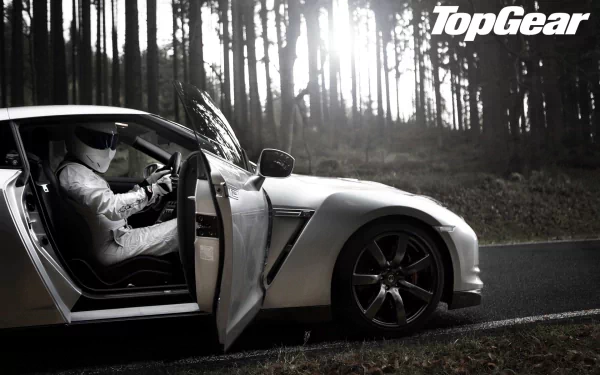 HD wallpaper featuring The Stig from Top Gear, possibly Ben Collins, in a sports car with a forest backdrop.