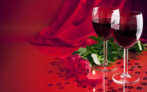 Two glasses of red wine sit beside a rose and a flickering candle on a red backdrop, creating a romantic Valentine's Day scene in this vibrant 4K Ultra HD wallpaper.