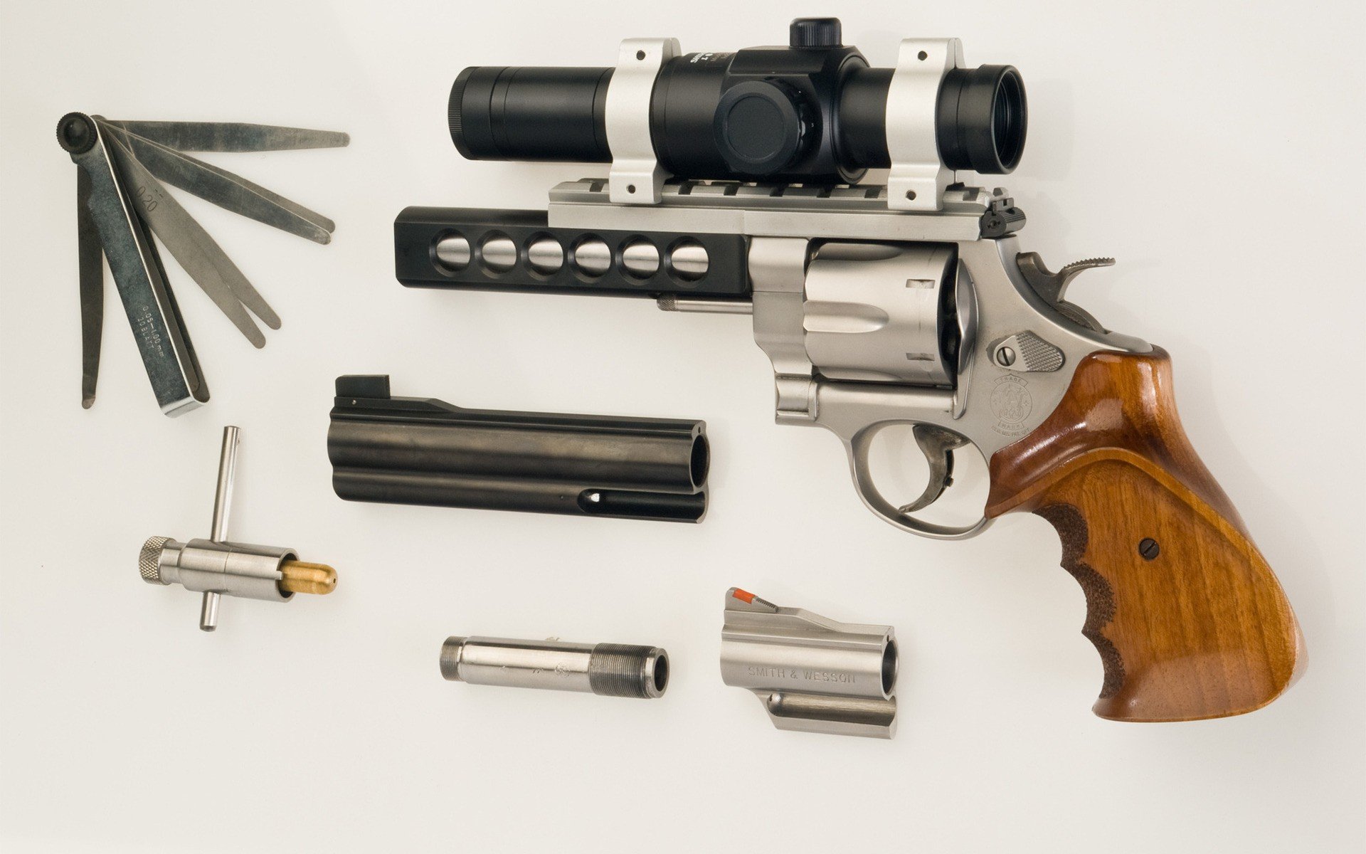 HD desktop wallpaper featuring a detailed man-made Smith & Wesson revolver with wooden grip and disassembled parts laid out on a white background.