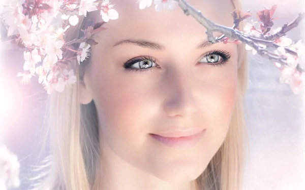 HD desktop wallpaper featuring a close-up of a woman's face, framed by delicate cherry blossom branches with soft, glowing light in the background.