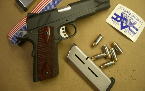 An HD desktop wallpaper featuring a Colt 1911 handgun, complemented by bullets and a patriotic ribbon. The composition emphasizes the craftsmanship of the firearm.