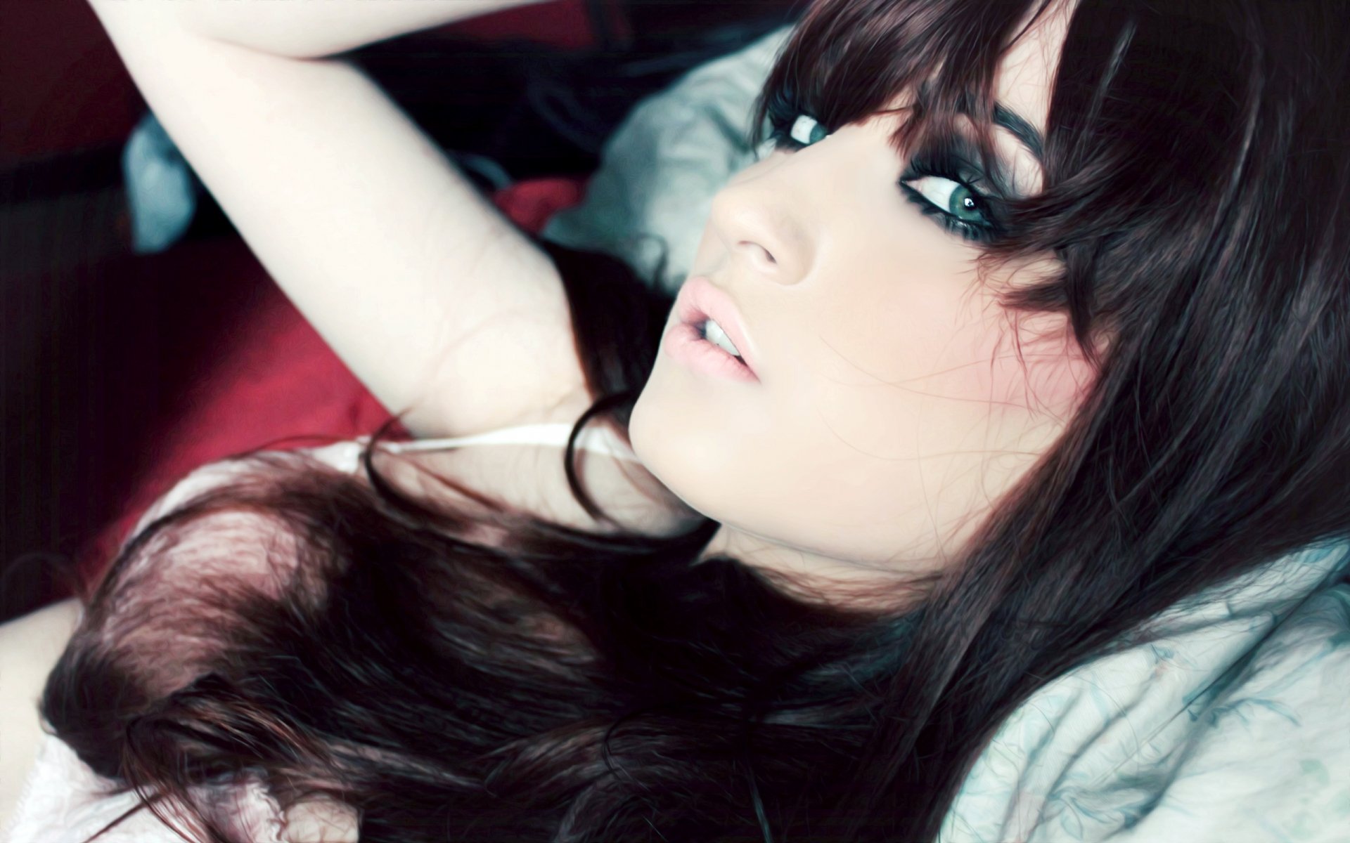 Beautiful woman with long dark hair and smoky eye makeup reclining on a bed, 2K Quad HD PC desktop wallpaper and background.