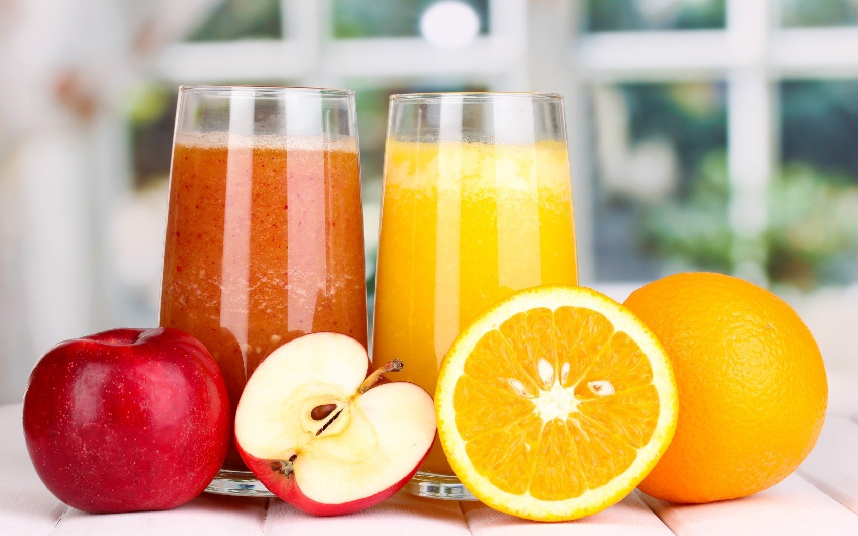 HD PC desktop wallpaper featuring fresh apple and orange juices with whole and sliced fruits, highlighting vibrant colors in a bright, natural setting.