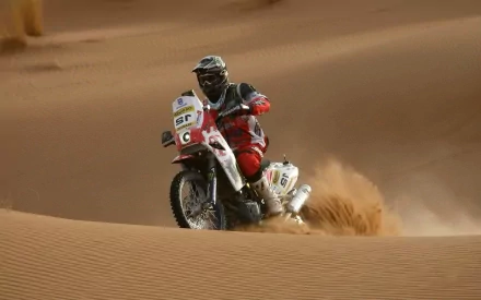 HD desktop wallpaper showing a motocross rider racing through sandy desert terrain, capturing dynamic motion and the thrill of off-road sports.