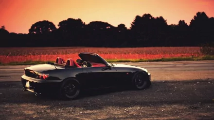 HD wallpaper of a Honda S2000 parked at sunset with a warm sky in the background.