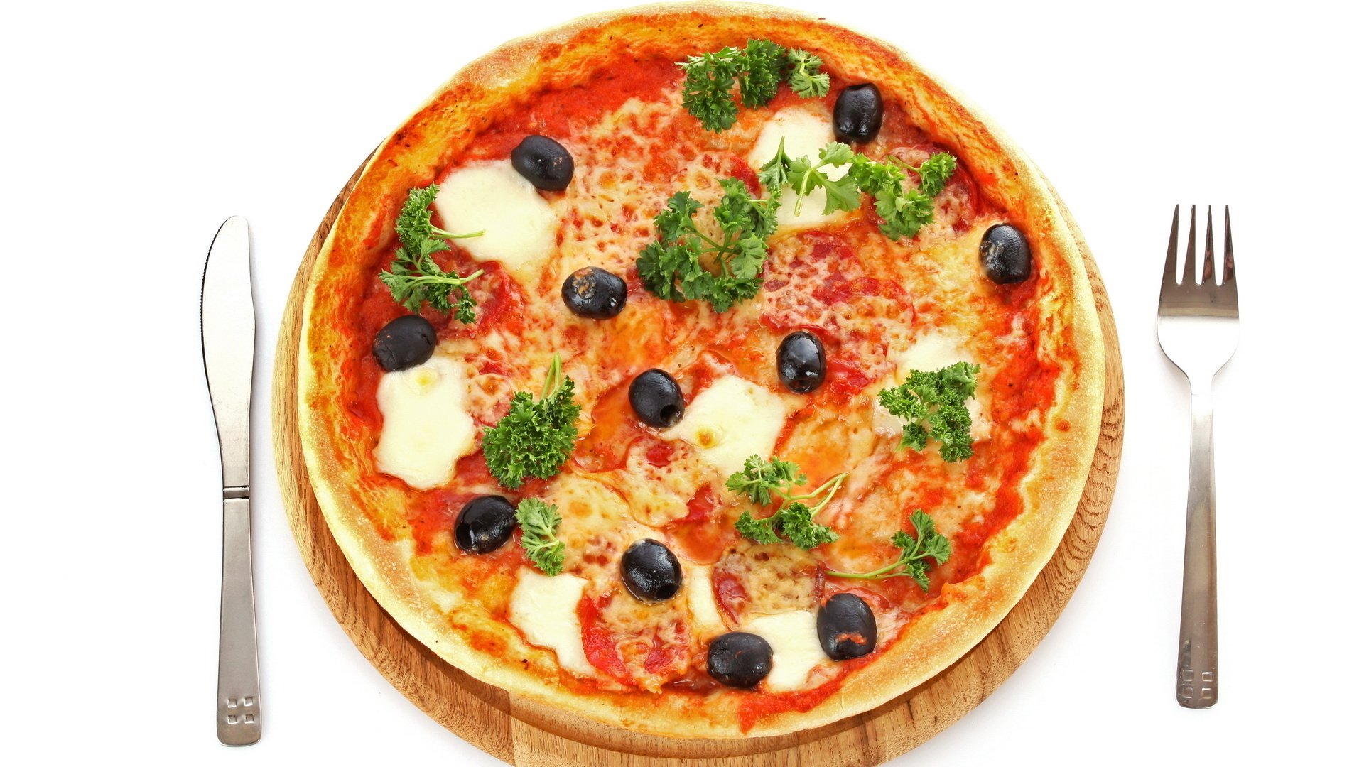 HD PC desktop wallpaper of food — a whole pizza topped with black olives, melted mozzarella, tomato sauce and parsley on a wooden board between fork and knife.