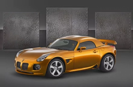 HD PC desktop wallpaper featuring a sleek gold Pontiac Solstice sports car against a minimalist industrial backdrop.