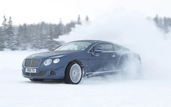 HD PC desktop wallpaper featuring a Bentley Continental GT driving through snowy terrain, showcasing the vehicle's sleek design and performance in winter conditions.