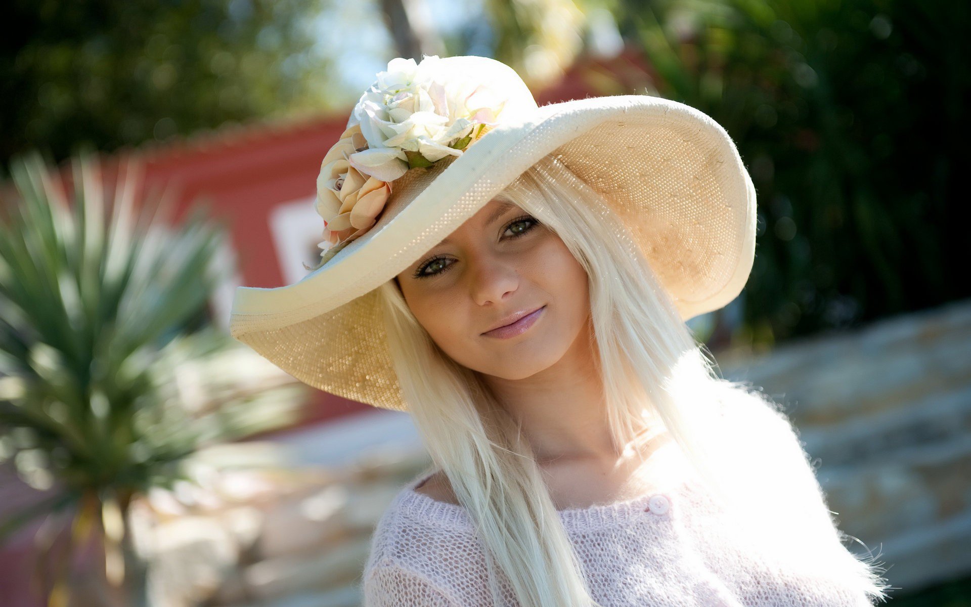 A woman model wearing a large, floral sunhat smiles warmly, captured in bright, natural light. This HD image makes a vibrant desktop wallpaper and background.