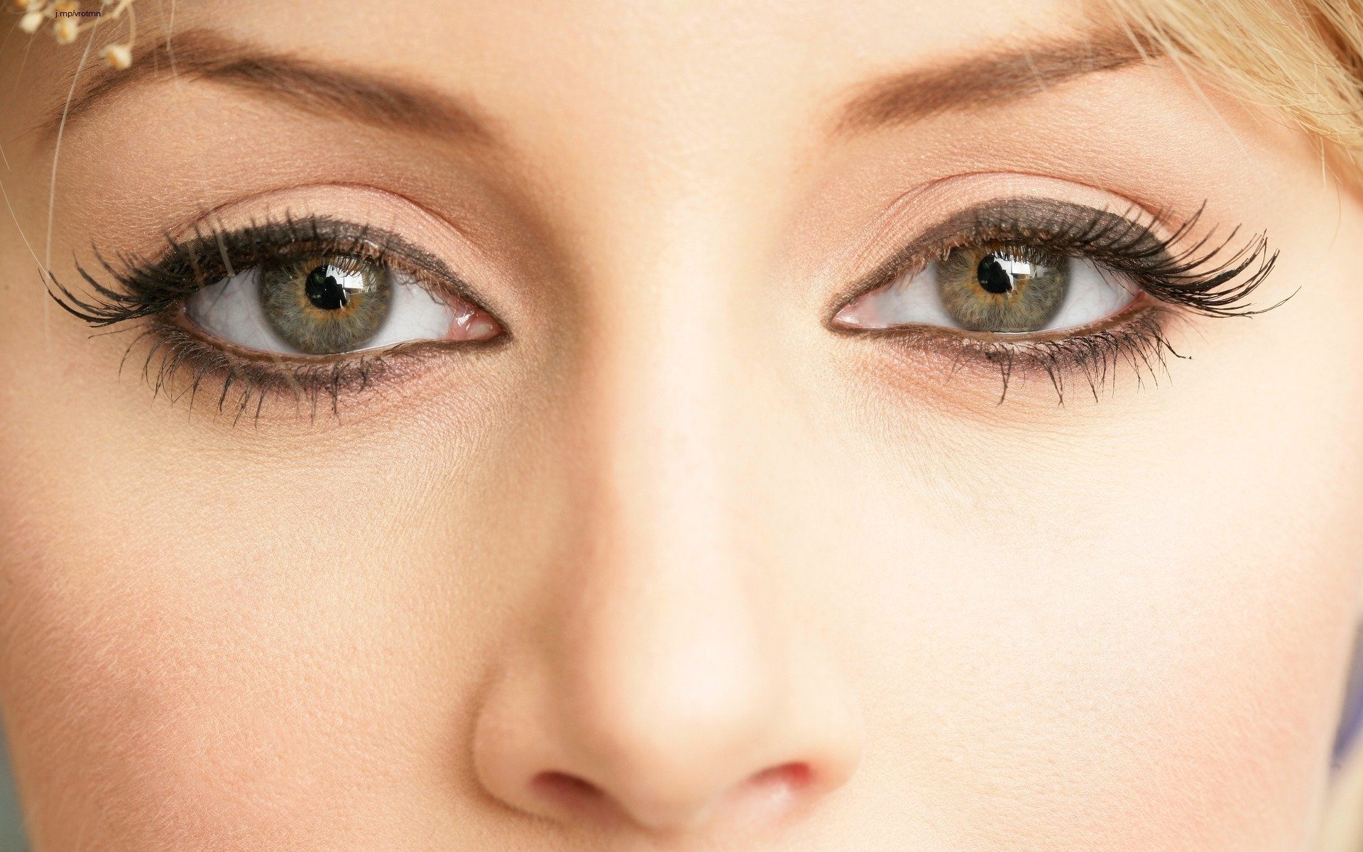 Close-up HD desktop wallpaper of a woman's face focusing on her green eyes with long eyelashes.