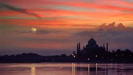 A stunning HD wallpaper featuring the Taj Mahal silhouetted against a vibrant sunset, reflecting on calm waters, creating a serene and enchanting atmosphere.