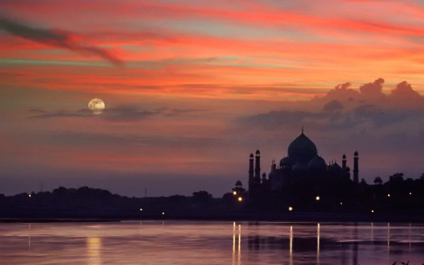 A stunning HD wallpaper featuring the Taj Mahal silhouetted against a vibrant sunset, reflecting on calm waters, creating a serene and enchanting atmosphere.