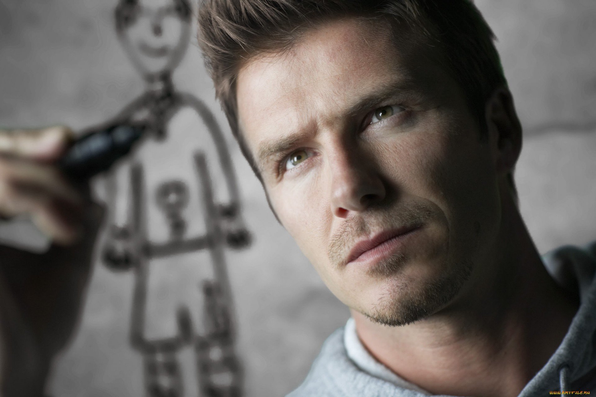 David Beckham looks thoughtfully at a drawing as he sketches in this HD desktop wallpaper, showcasing his artistic side alongside his sports legacy.