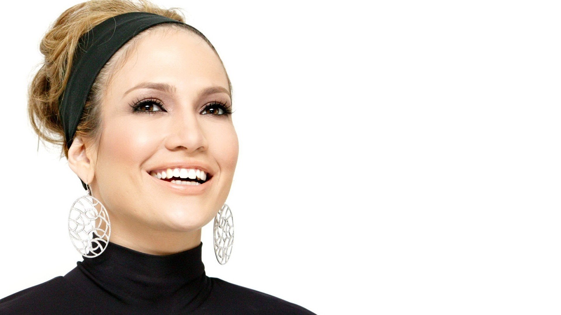A vibrant HD desktop wallpaper featuring celebrity Jennifer Lopez, showcasing her smiling face, stylish earrings, and a chic black outfit against a clean, white background.