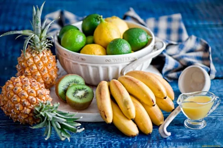 A vibrant assortment of fruits including pineapples, bananas, kiwifruit, and citrus, arranged on a blue background, creating a fresh and colorful HD desktop wallpaper.