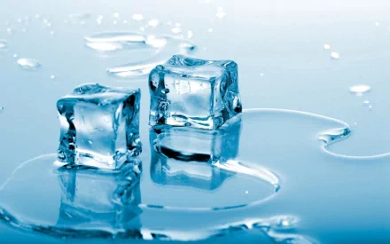 Two clear ice cubes sit on a smooth surface, surrounded by small droplets of water, creating a serene and refreshing atmosphere. This high-definition photography serves as a beautiful desktop wallpaper.