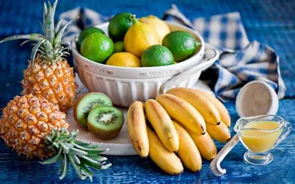 A vibrant assortment of fruits including pineapples, bananas, kiwifruit, and citrus, arranged on a blue background, creating a fresh and colorful HD desktop wallpaper.