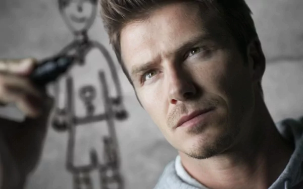 David Beckham looks thoughtfully at a drawing as he sketches in this HD desktop wallpaper, showcasing his artistic side alongside his sports legacy.