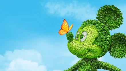 HD Disney movie desktop wallpaper showing a topiary shaped like Mickey Mouse with a butterfly perched on its nose against a bright blue sky background.