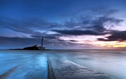 HD desktop wallpaper showing a man-made lighthouse on a small island against a dramatic sunset sky over calm ocean waters.