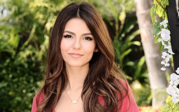 A vibrant HD desktop wallpaper featuring celebrity Victoria Justice, captured in a serene outdoor setting with lush greenery and soft lighting.