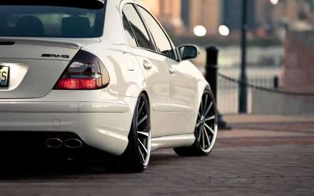 A sleek white Mercedes-Benz E-Class parked with stylish black rims, featuring a modern urban backdrop. This high-definition image serves as a striking desktop wallpaper.