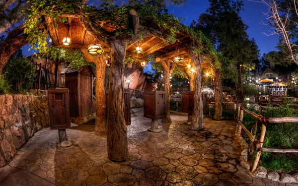 Nighttime photography captures a warmly lit rustic outdoor place with tree trunks, lanterns, and stone pathways, presented as an HD PC desktop wallpaper and background.