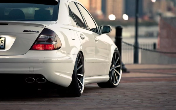 A sleek white Mercedes-Benz E-Class parked with stylish black rims, featuring a modern urban backdrop. This high-definition image serves as a striking desktop wallpaper.